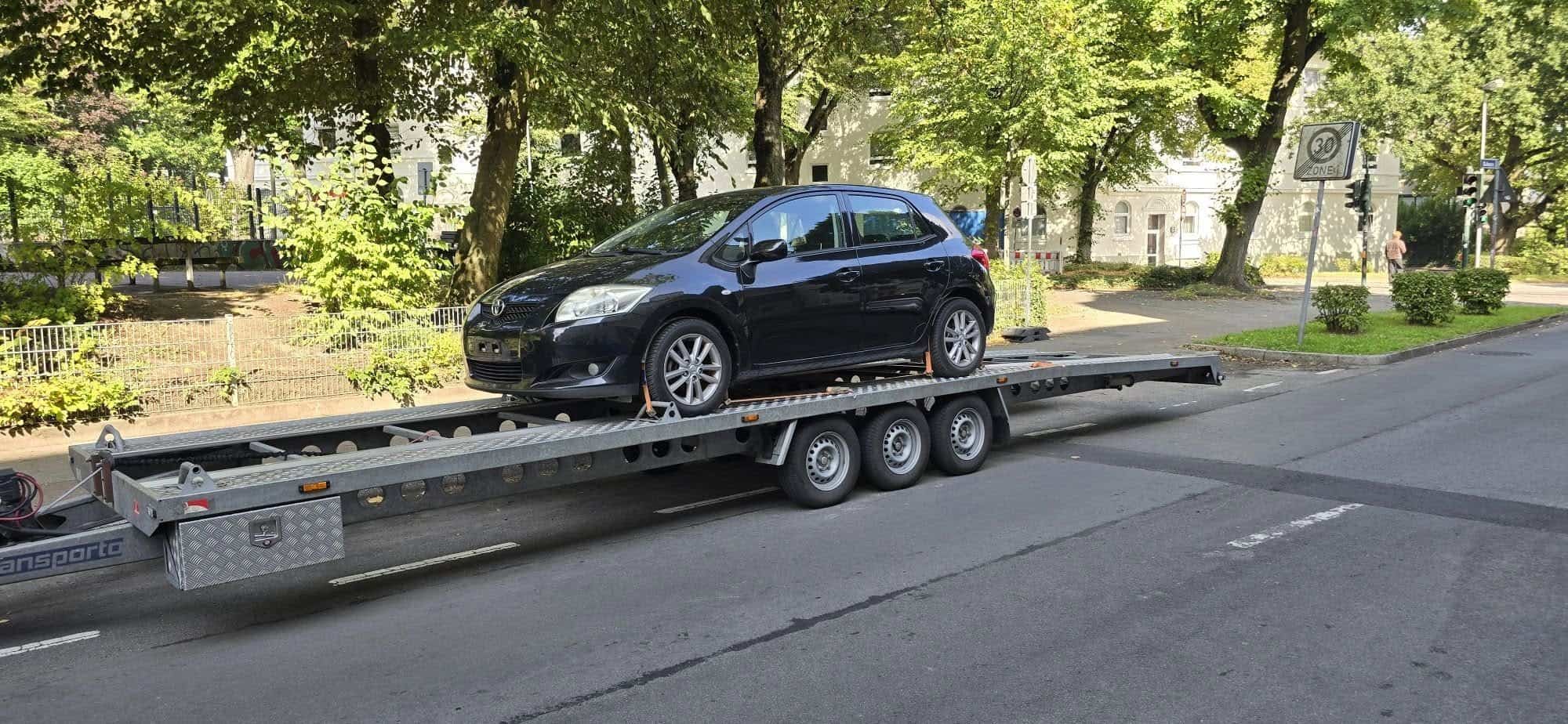 Zwarte Toyota Auris op de autoaanhanger tijdens het ophalen in Duitsland